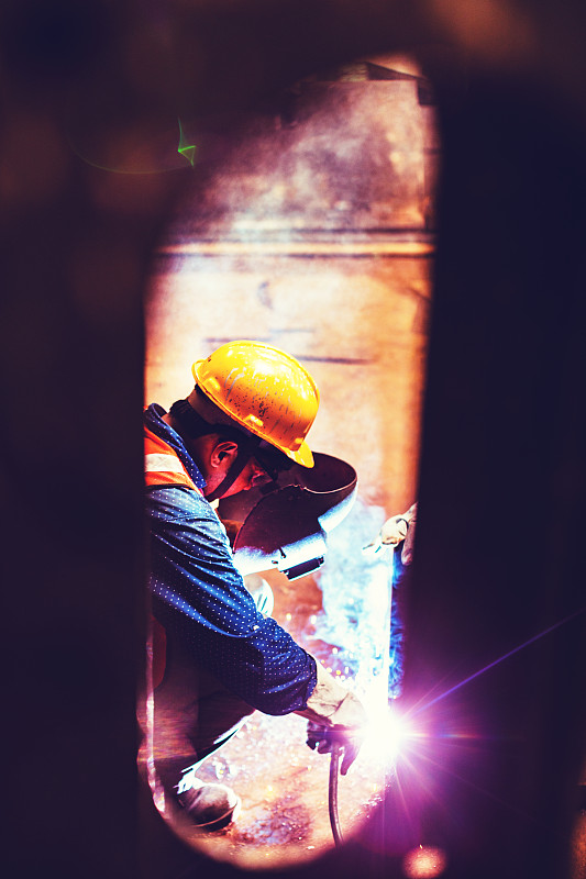 小景是一个蓝领工人在工厂忙着焊接一些金属零件。图片下载
