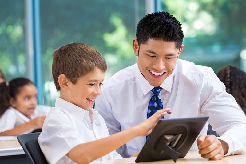小学学生使用数字平板电脑与亚洲教师图片下载