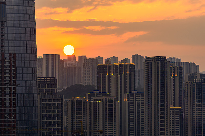 黄昏时分一轮红日悬在都市鳞次栉比的高楼建筑群之上图片下载