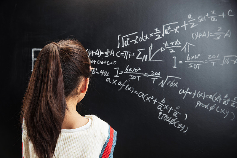 小女孩思考黑板上的数学题图片素材