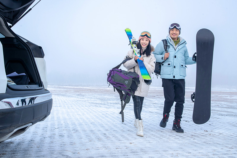 停车场上青年伴侣拿着滑雪板图片下载