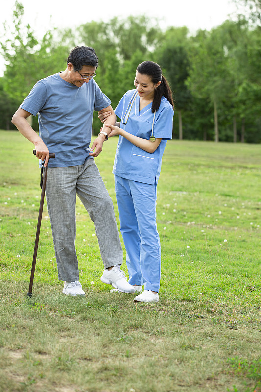 女护士指导老年男人练习运动在户外疗养院的公园里图片下载
