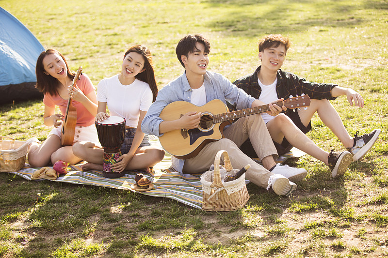 快乐的年轻人在户外野餐玩音乐图片素材