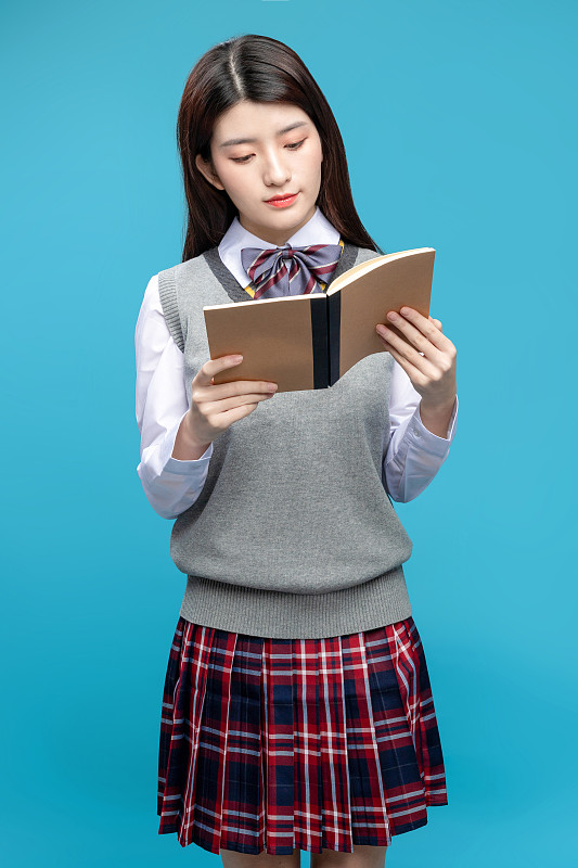 蓝色背景里拿着书本的中国女学生图片下载