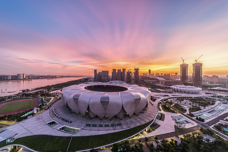 日出时分下的杭州亚运会奥体博览城主体育场五彩斑斓光彩照耀图片下载