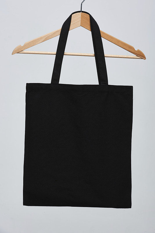 黑色可重复使用袋挂在木制衣架上图片素材