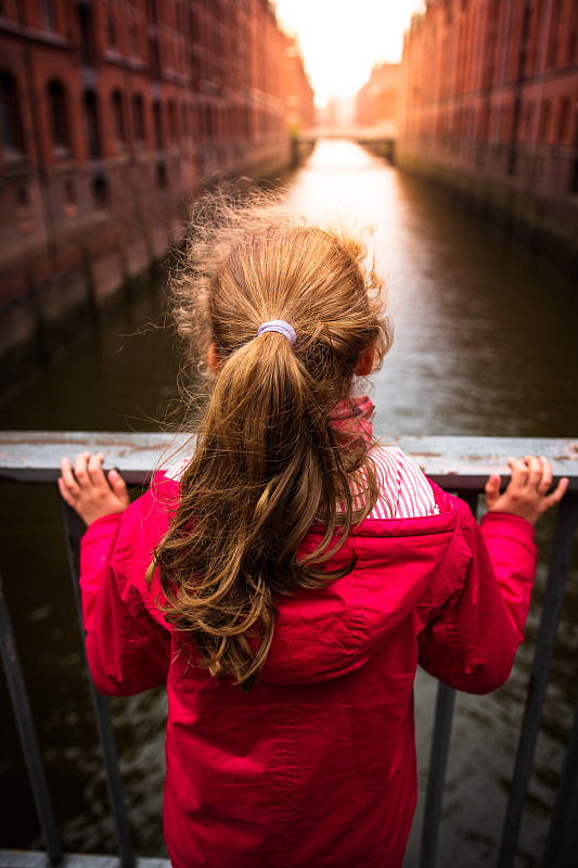 德国阿尔茨塔特市，站在运河桥上的女孩的后视图图片下载