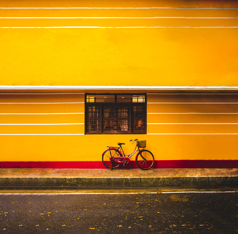 红色自行车和篮子靠在黄色建筑，白城，印度图片下载