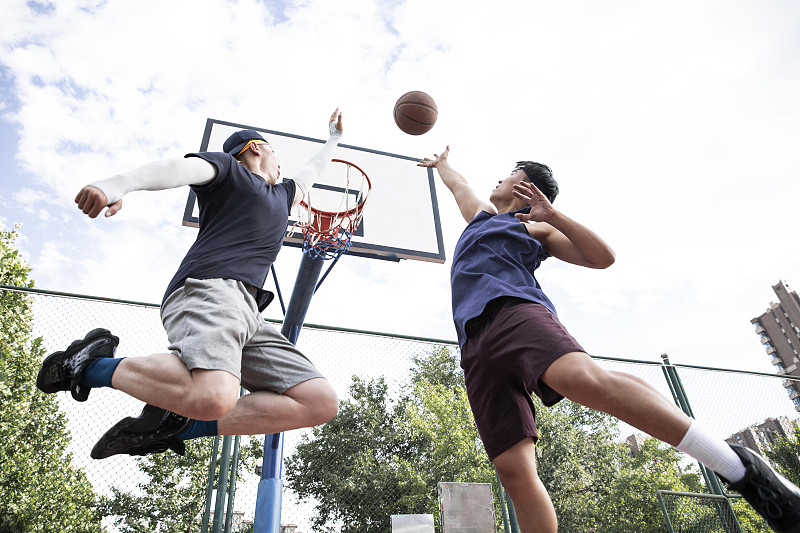 两个青年男子在学校篮球场打篮球比赛图片下载