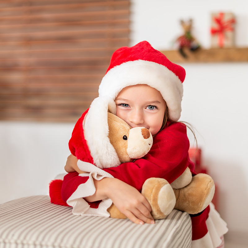 可爱的小女孩抱着她的圣诞礼物，柔软的玩具泰迪熊，斯洛伐克图片下载