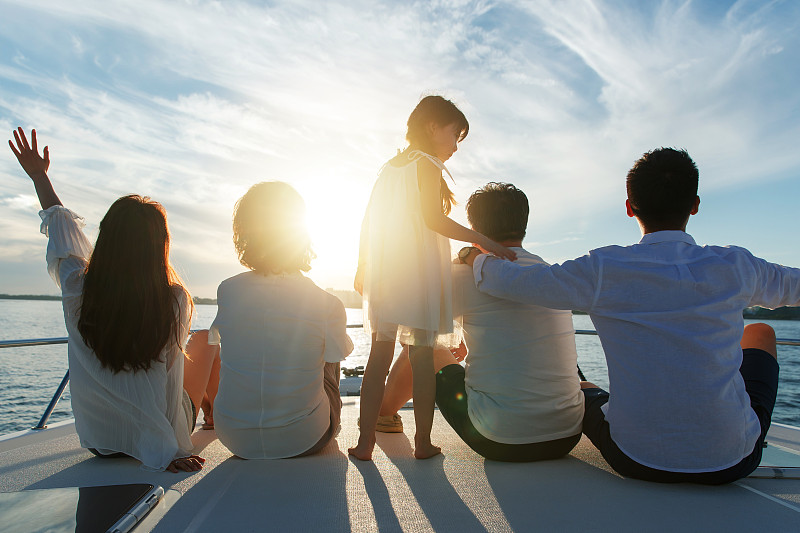 夕阳下坐在游艇上的快乐一家人图片下载