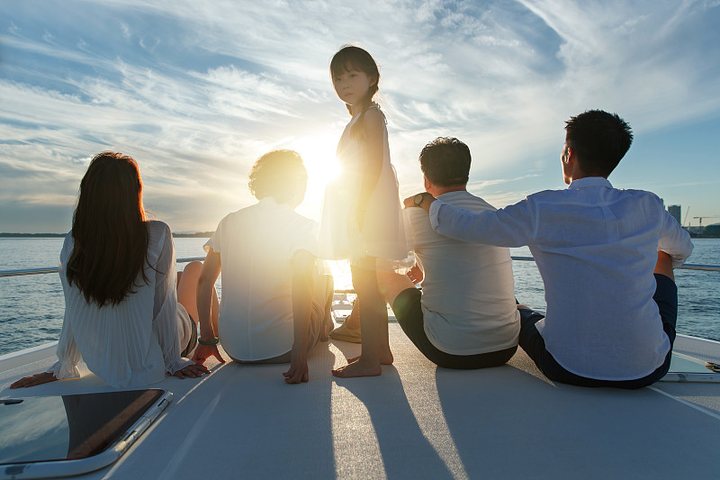 夕阳下坐在游艇上的快乐一家人图片素材