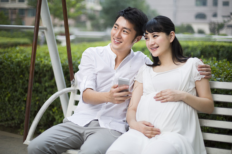 丈夫和怀孕的妻子在摇椅上听音乐图片下载