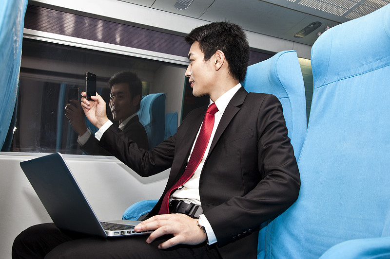 年轻商务男士在车厢内使用笔记本电脑图片下载
