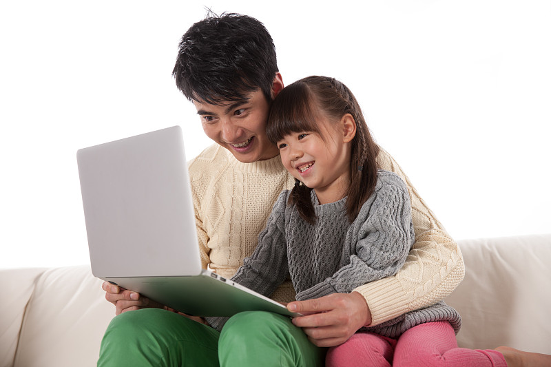 父亲和女儿坐在沙发上使用掌上电脑图片素材