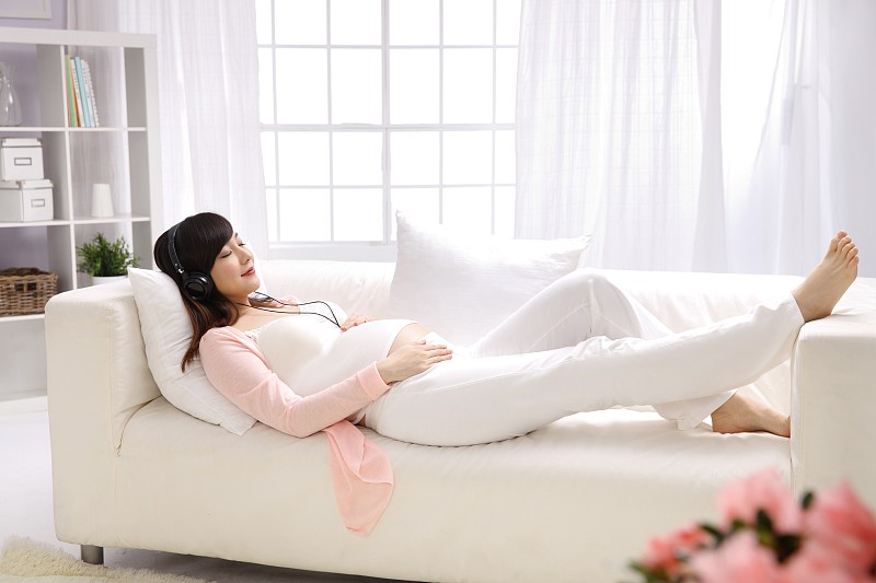 孕妇躺在沙发上听音乐图片素材