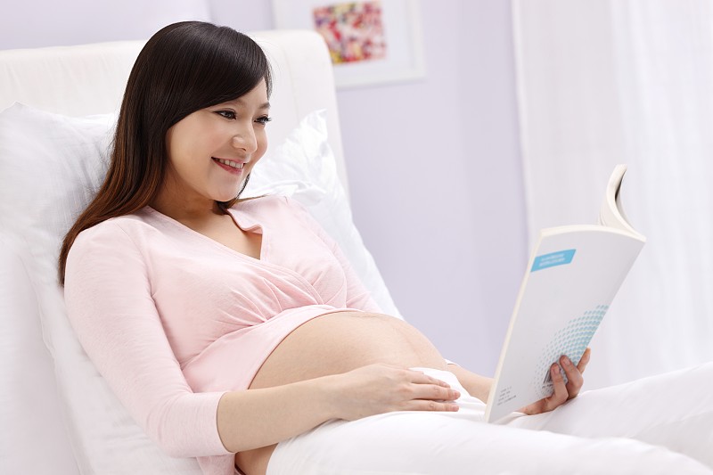 孕妇坐在床上看书图片下载