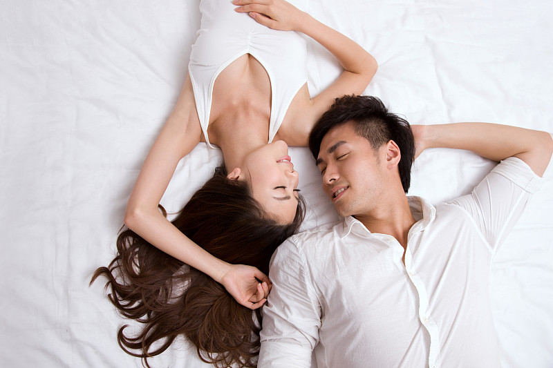东方年轻夫妇躺在床上睡觉图片下载