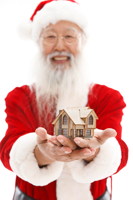 穿着圣诞服的老年人手捧着房屋模型图片素材