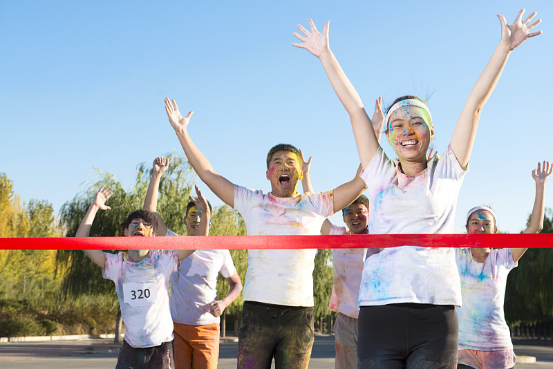 Young woman crossing finishing line at The Color Run图片下载