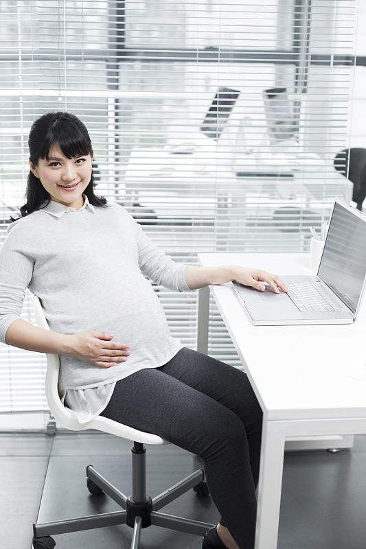 怀孕的商务女士使用笔记本电脑图片素材