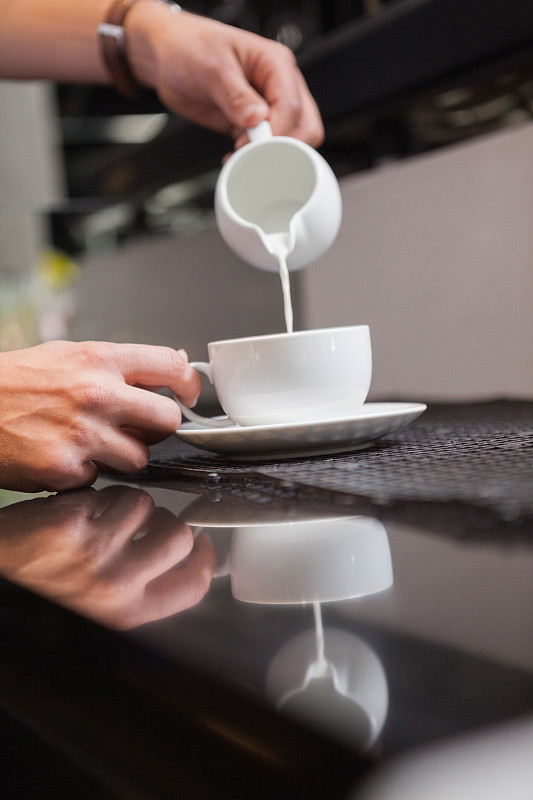 咖啡馆里的咖啡师把牛奶倒进咖啡里图片下载