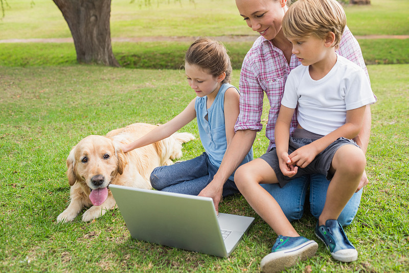 快乐的家庭和他们的狗在一个阳光明媚的日子使用笔记本电脑图片下载