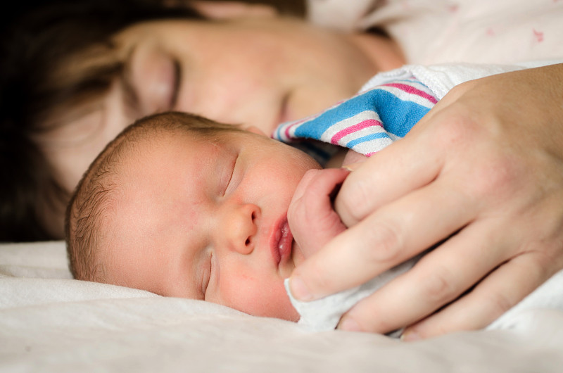 在医院分娩后躺在母亲旁边的新生儿图片下载