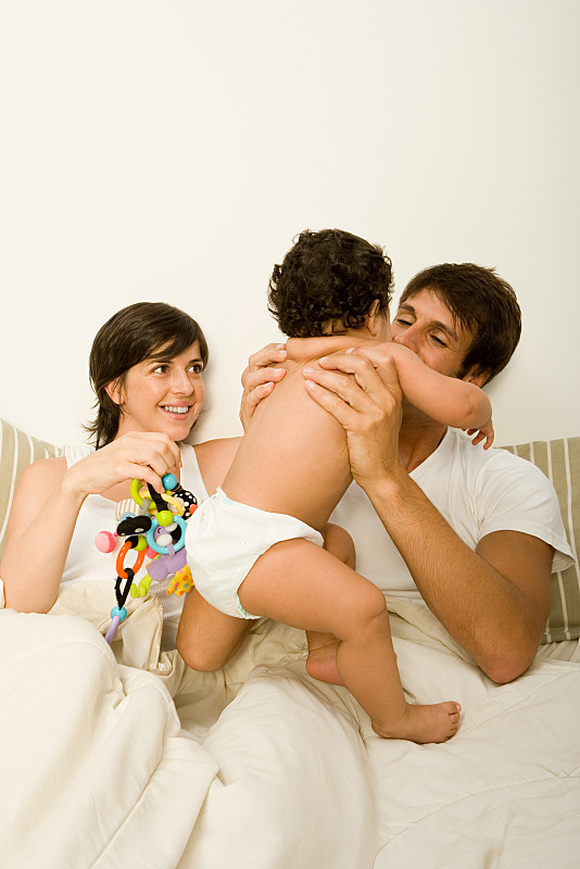 一对夫妇和婴儿在床上图片下载