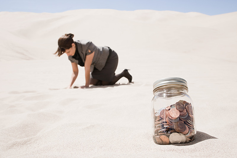 在沙漠中寻找一罐硬币的女人图片下载