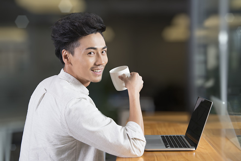 Creative businessman using laptop in break room图片下载