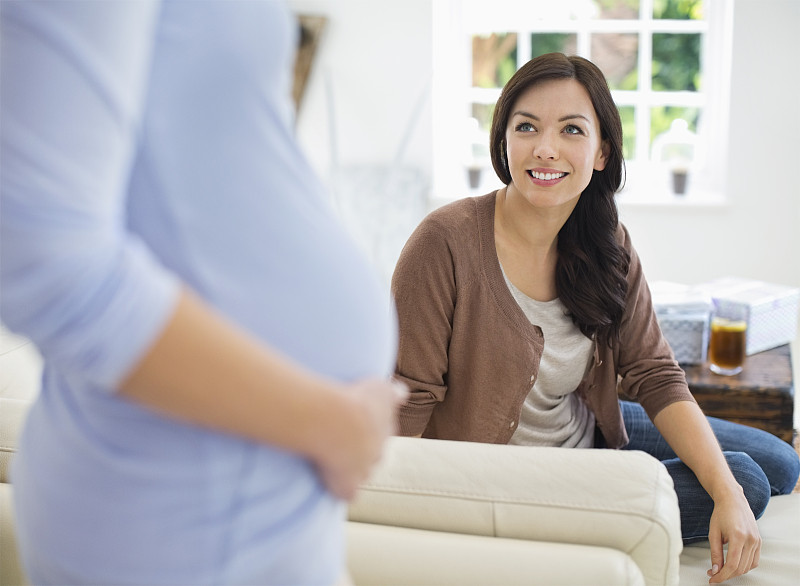 女人对着怀孕的朋友微笑图片下载