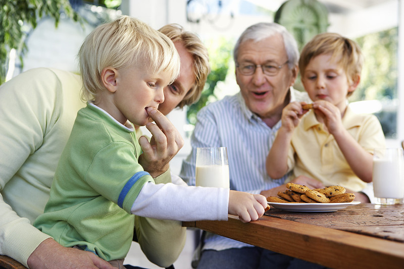 和父亲在餐桌上吃饼干和牛奶的男孩图片素材