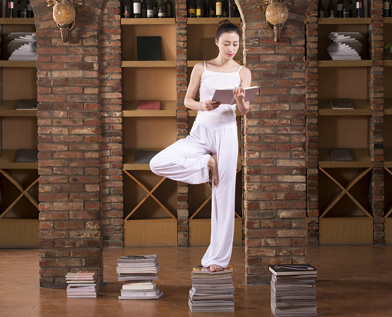 站在书上练习瑜伽的青年女子图片素材