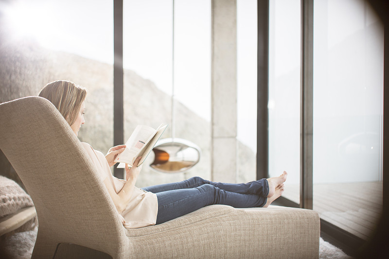 在现代客厅的沙发上看书的女人图片下载