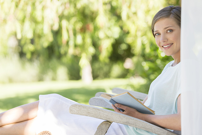 在户外草坪椅上看书的女人图片下载
