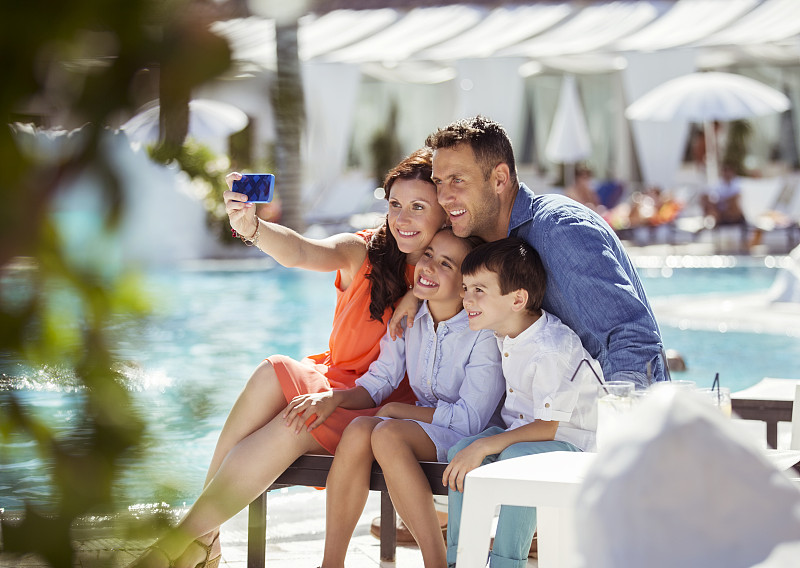 一家人和两个孩子在度假胜地的游泳池自拍图片素材