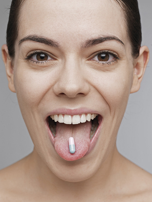 维他命药片在年轻女人的舌头上图片下载