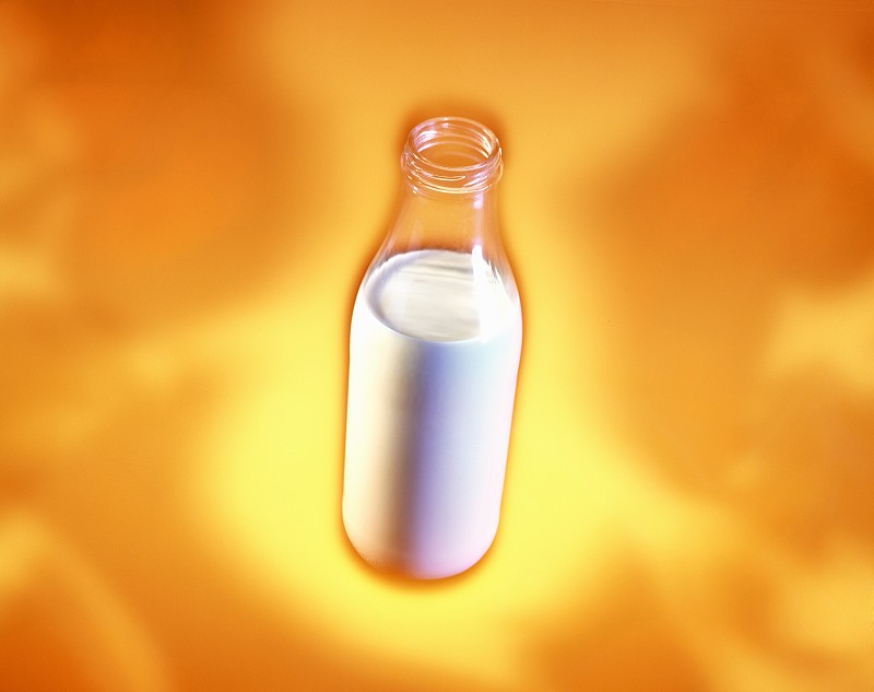 橙色背景下的一瓶牛奶图片下载