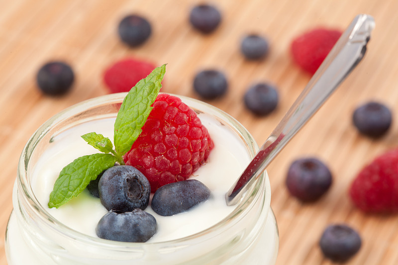 一个罐子酸奶与薄荷蓝莓和覆盆子后面展示的特写图片下载