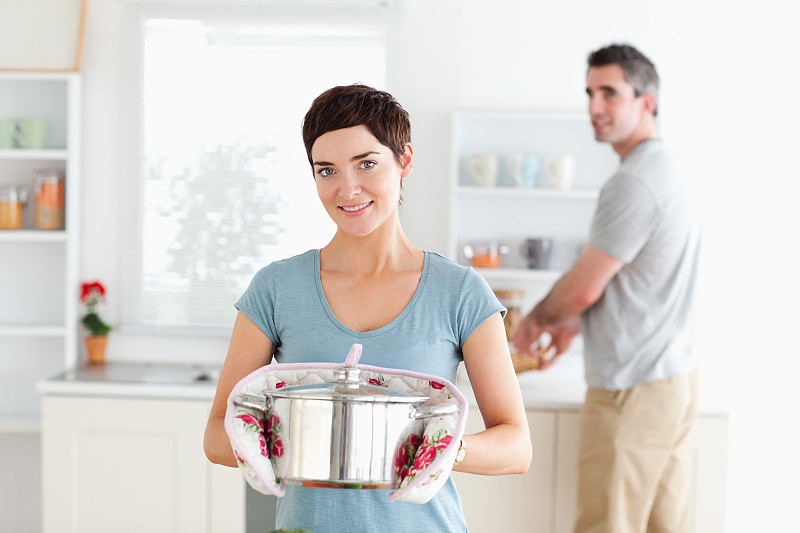 女人拿着锅，男人在厨房洗碗图片下载