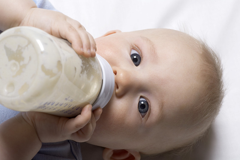 男婴用奶瓶喝水的照片摄影图片下载