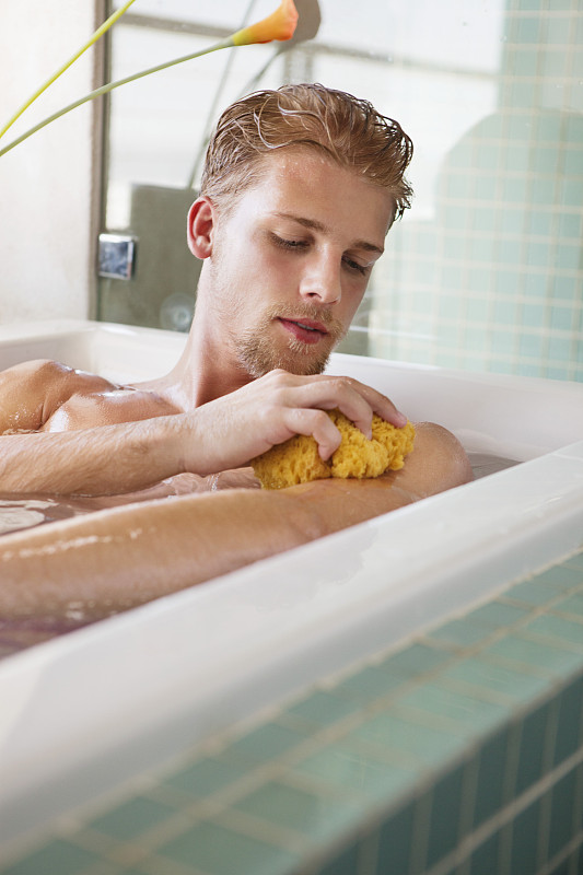 在浴缸里擦洗身体的男人图片下载