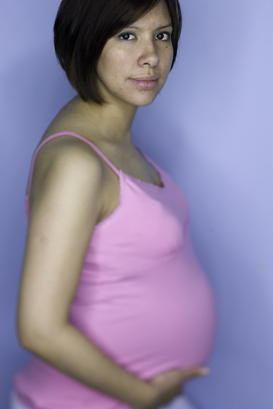 孕妇抱着肚子在摄影棚里拍照图片下载
