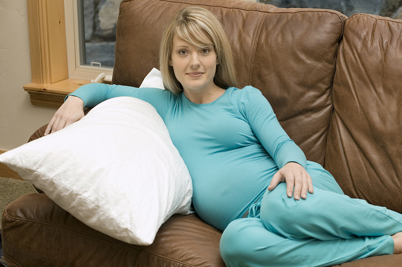 年轻孕妇躺在沙发上，画像图片下载
