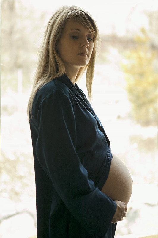 孕妇站在家里的窗户旁，肖像图片下载