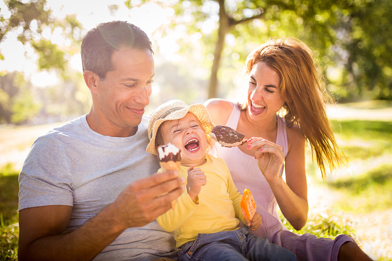 年轻的家庭在公园里愉快地吃着冰淇淋图片下载