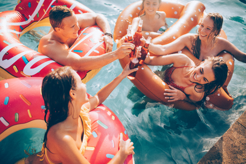 朋友们在泳池里喝着瓶装饮料庆祝夏天图片素材