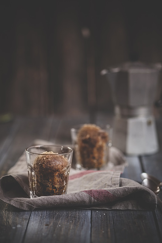 两杯格兰尼塔咖啡，厨房毛巾和浓咖啡罐放在深色木头上图片素材