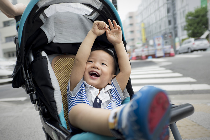 小男孩微笑着坐在婴儿车里图片下载